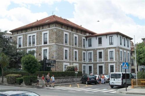 ein großes Backsteingebäude mit Leuten, die davor laufen in der Unterkunft Hotel Luzon in San Vicente de la Barquera