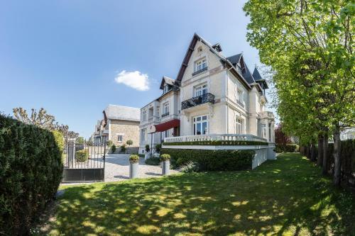 una grande casa bianca con cortile di Villa 81 a Deauville