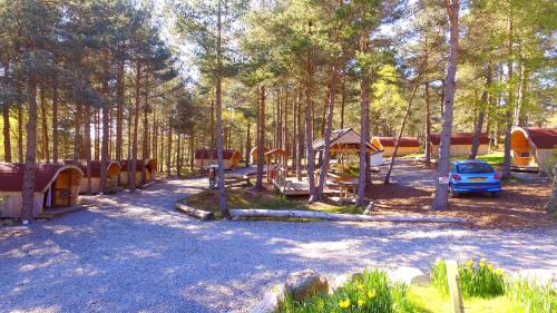 un parc avec une aire de jeux et une voiture dans les bois dans l'établissement Camping Pod Heaven, à Brackla