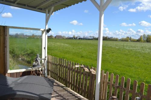 un porche con una valla y vistas a un campo en Bed & Breakfast Boszicht Leeuwarden, en Leeuwarden