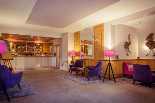 un hall avec des chaises et des tables violets ainsi qu'un bar dans l'établissement Hotel am Rugard, à Bergen auf Rügen