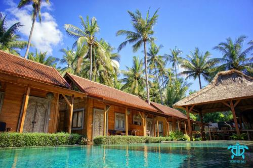 un complejo con piscina y palmeras en Benthos Bali Dive Resort, en Candidasa