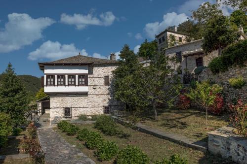 uma antiga casa de pedra com um jardim em frente em Urania Traditional Stone House em Pinakátai