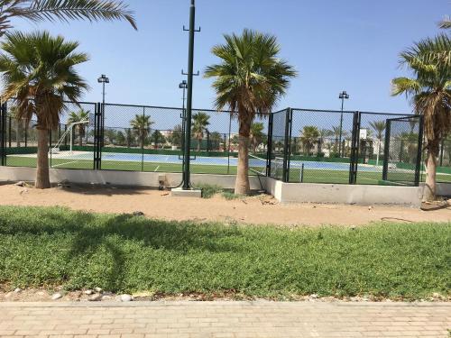 einen Zaun mit Palmen vor einem Tennisplatz in der Unterkunft Apartment in Jebel Sifah in As Sīfah