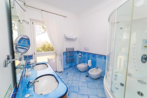 Baño azul con 2 lavabos y 2 aseos en Villa Eliana, en Sorrento