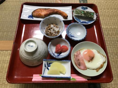 een rood dienblad gevuld met voedsel op een tafel bij Niko Ryokan in Aizuwakamatsu