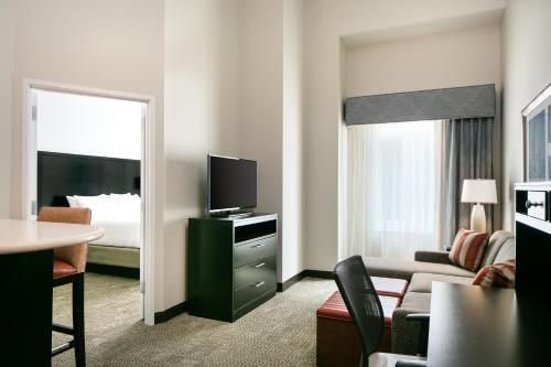 uma sala de estar com um quarto com uma cama e uma televisão em Staybridge Suites Des Moines Downtown, an IHG Hotel em Des Moines