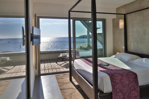 een slaapkamer met een bed en een balkon met uitzicht op de oceaan bij Royal Antibes - Luxury Hotel, Résidence, Beach & Spa in Antibes