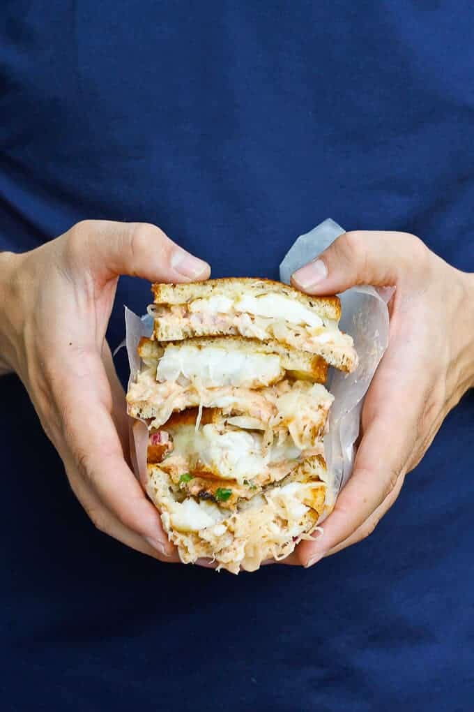 Holding a Stack of Cod Reuben Sandwiches.