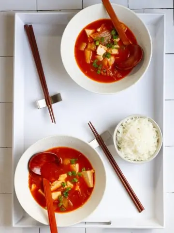 Vegan kimchi soup in bowls on a serving tray