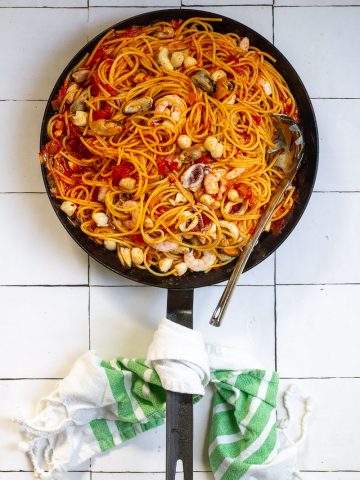 Seafood fra diavolo with pasta, seafood, and tomatoes in skillet.