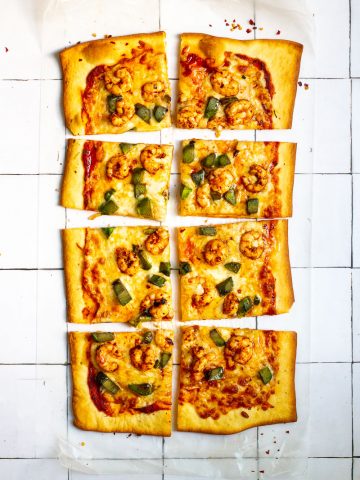 Spicy shrimp pizza cut into 8 square slices.