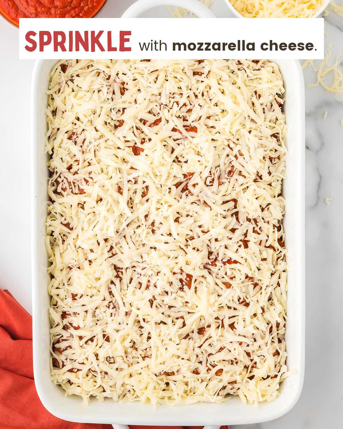 Shredded mozzarella cheese on top of a casserole in a baking dish.