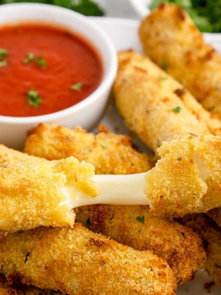 Air Fryer Mozzarella Sticks served on a white plate with marinara sauce.