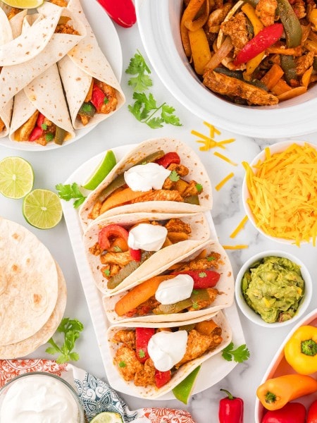 Top down view of Crockpot Chicken Fajitas served in soft taco wraps with all the toppings.