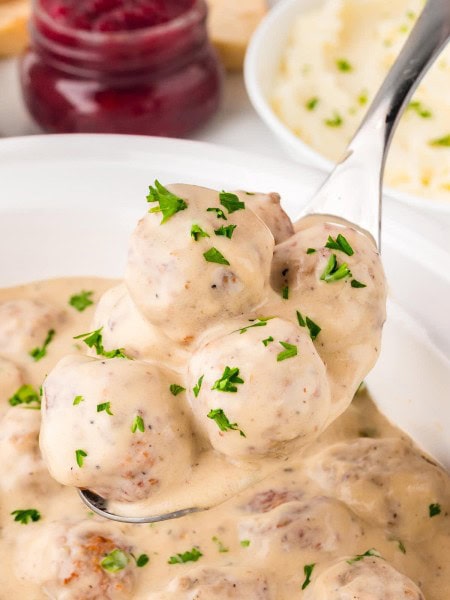 A serving spoon filled with Crockpot Swedish Meatballs.