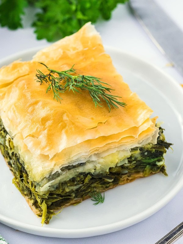 A slice of Spanakopita on a white plate.