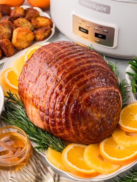 Crock Pot Ham on a white plate served with oranges and pineapples.