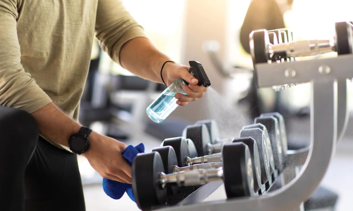 Wiping clean gym equipment to avoid germs, viruses, bacteria