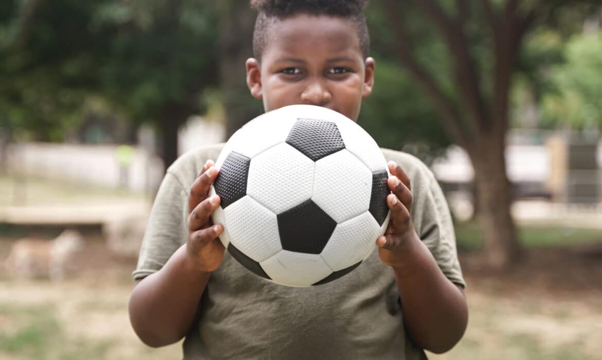 Overweight child holding soccer ball combating pediatric obesity