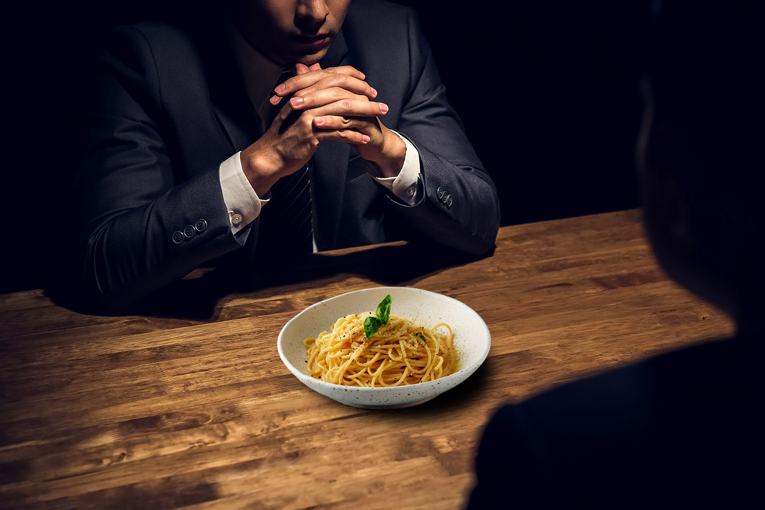 A detective at an interrogation table with a plate of cacio e pepe in front of him.