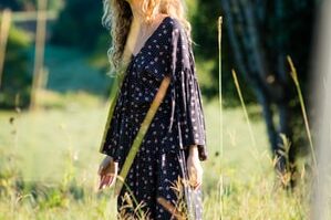 woman in black long-sleeved dress standing on grass field