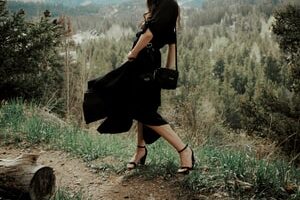 woman in black dress sitting on brown rock during daytime