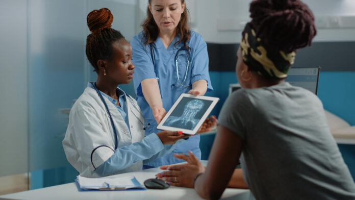 Doctor growing her medical practice by showing radiography diagnosis on digital device for healthcare examination to woman with disease.