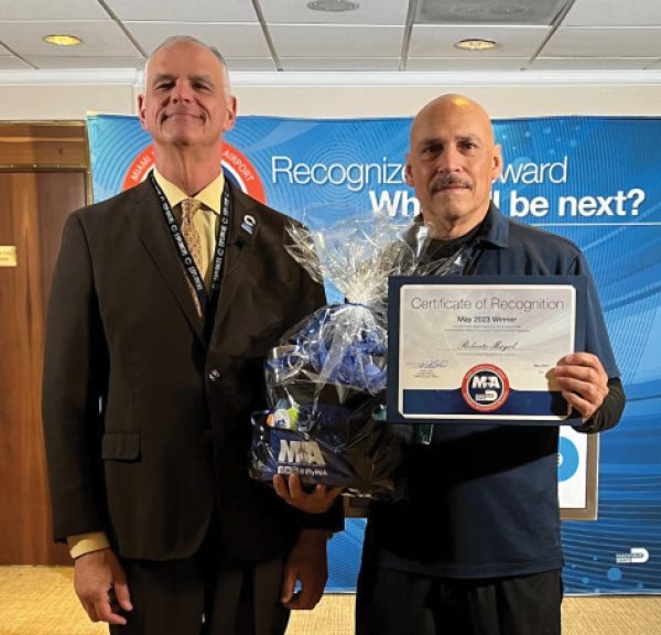 Two men standing next to each other holding an award.