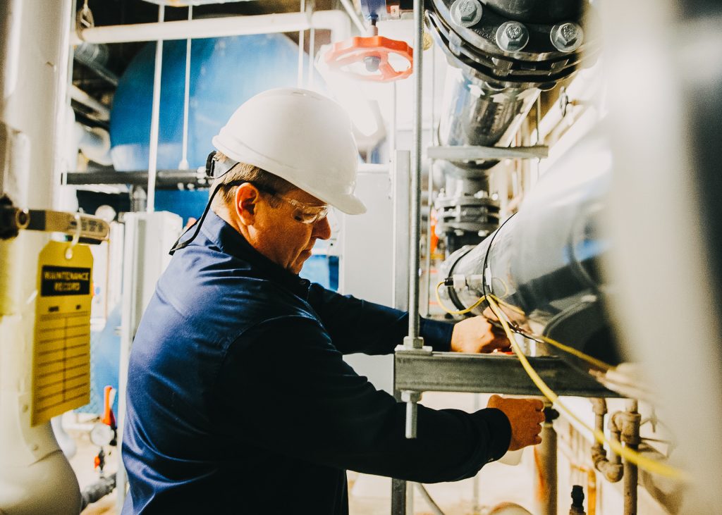 A man in a hard hat is working on a pipe.