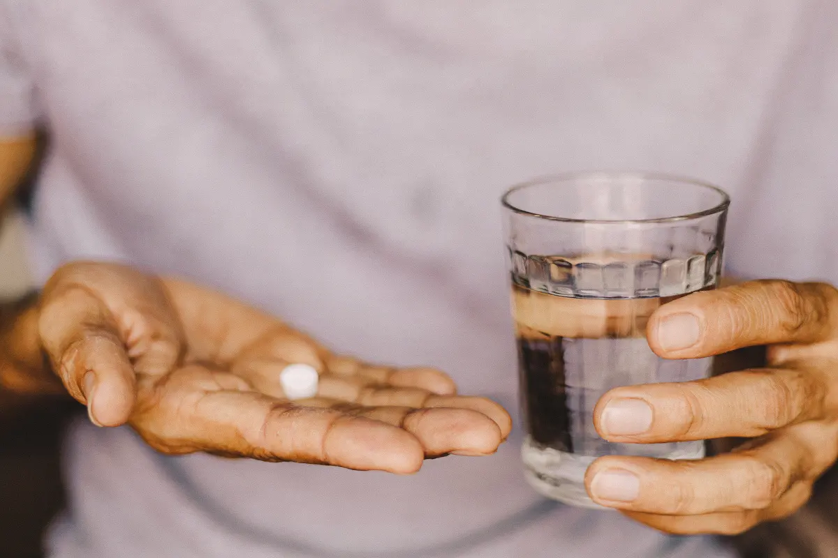 Person holding glass and pill