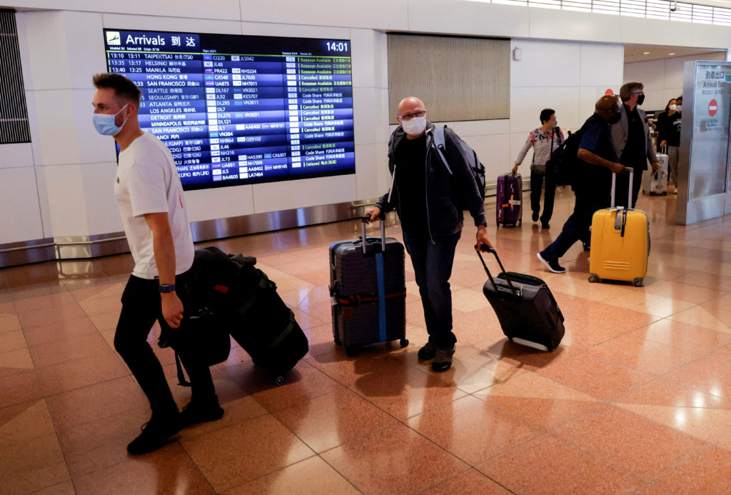 Foreign travelers walk upon their arrival at the Haneda International Airport, on the first day after Japan opened its doo...