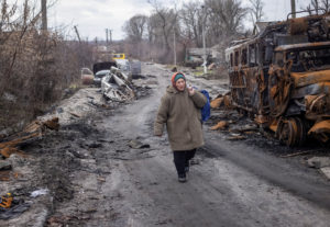 A local resident walks an empty street near destroyed vehicles in the village of Torske