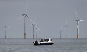 Two fishermen sit in their boat at the Gunfleet Sands Offshore Wind Farm near Clacton-on-Sea in southeast England