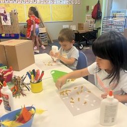 Preschoolers glue fusilli pasta onto paper.