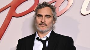 Joaquin Phoenix poses on a red carpet in a black tuxedo