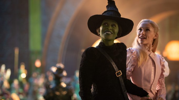 Cynthia Erivo as Elphaba and Ariana Grande as Glinda smile and hold hands in 'Wicked'.