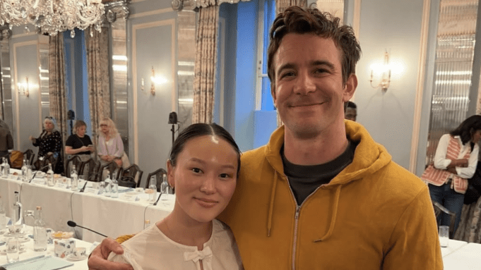 Yerin Ha and Luke Thompson pose for a photo in front of a huge regal table for a script read.