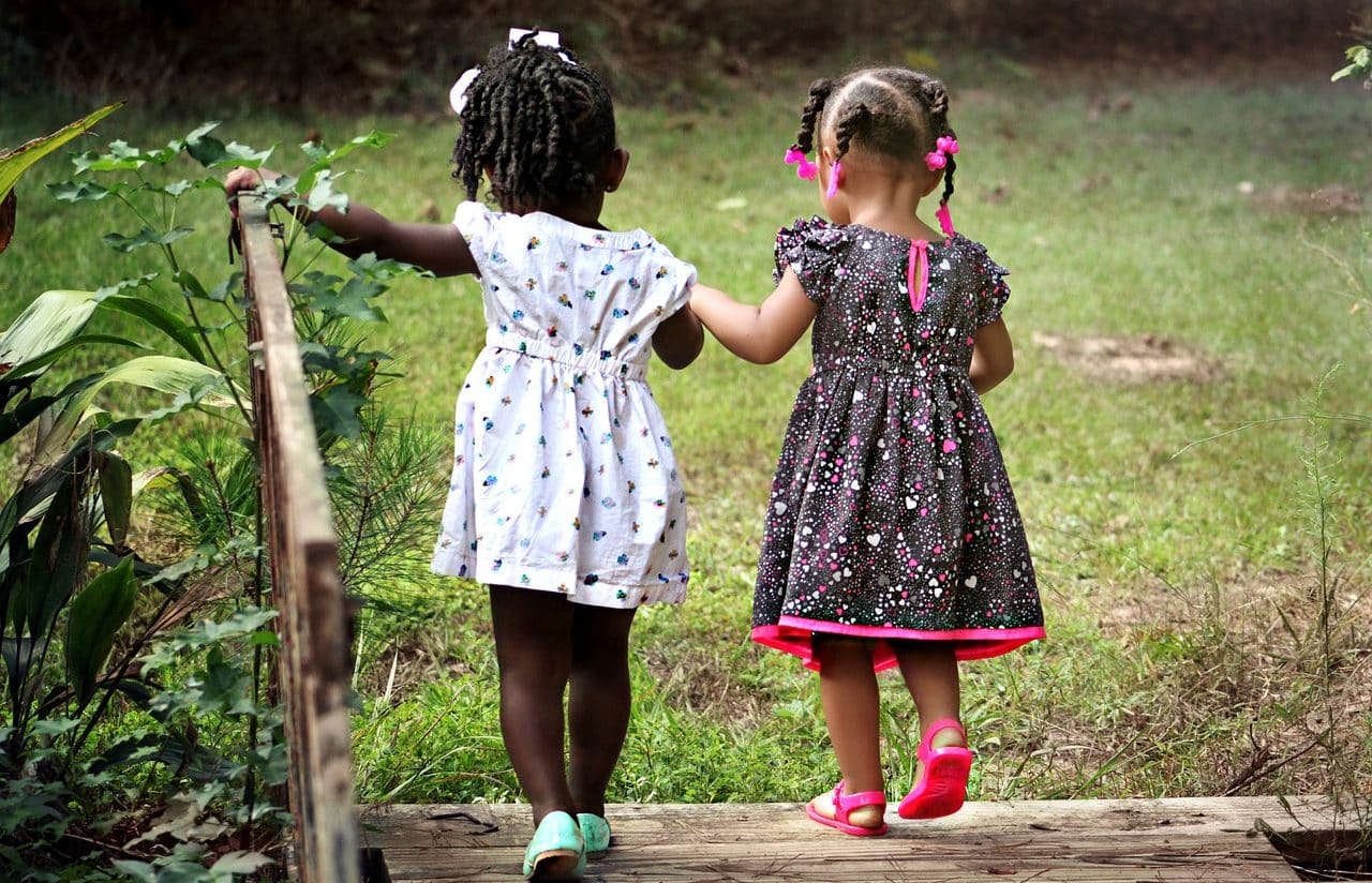 Dos niñas cruzando un puente en el campo