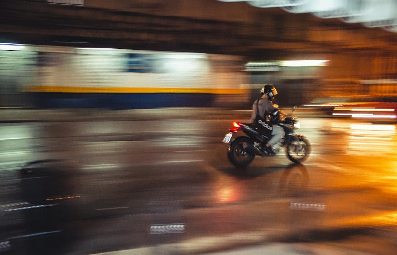 Persona viajando en motocicleta por la ciudad, con el fondo difuso con efecto de velocidad.