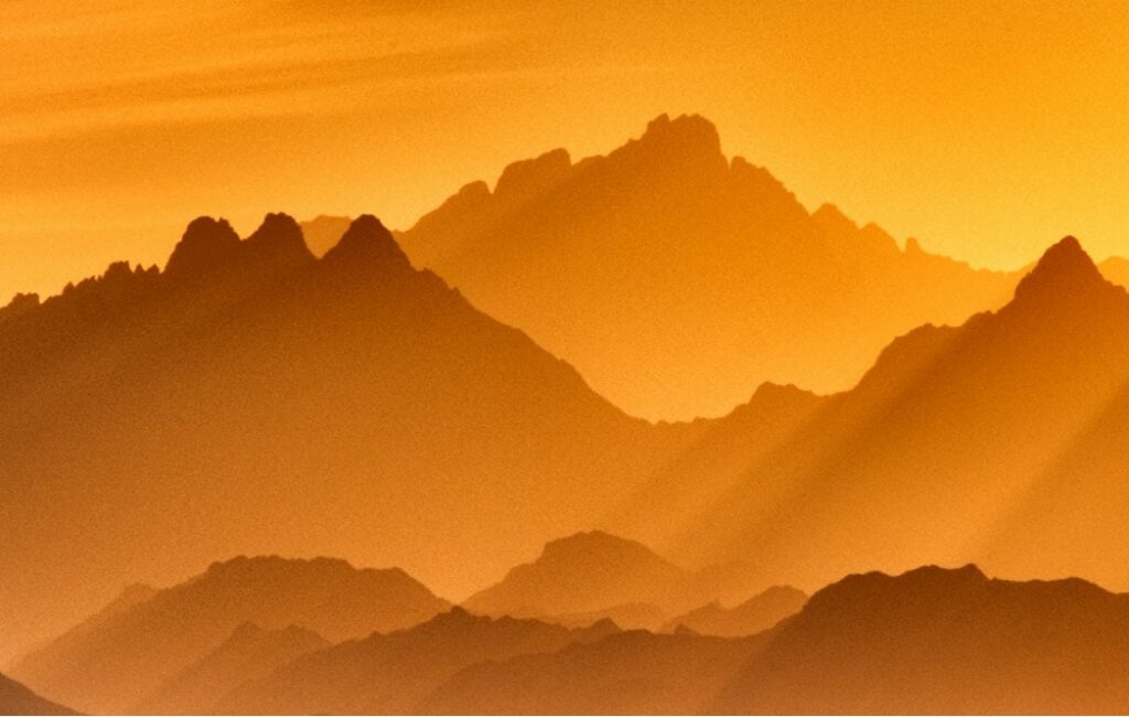 golden sun-soaked jagged mountains, rays of golden light hit them from the rhs