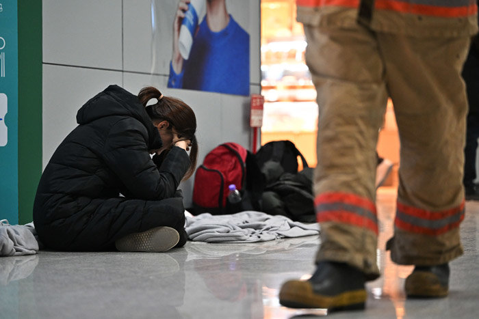 제주항공 여객기 사고 이튿날인 30일 오전 전남 무안국제공항 2층 대합실에서 한 유족이 주저앉아 머리를 붙잡고 있다. [뉴시스]