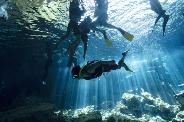 Tourists swim in the cenote "Dos Ojos," or Two Eyes, on the outskirts of Playa del Carmen, Mexico, Saturday, March 9, 2024. These glowing sinkhole lakes, known as cenotes, are a part of one of Mexico's natural wonders: A fragile system of thousands of subterranean caverns, rivers, and lakes that wind beneath Mexico's southern Yucatan peninsula. (AP Photo/Rodrigo Abd)