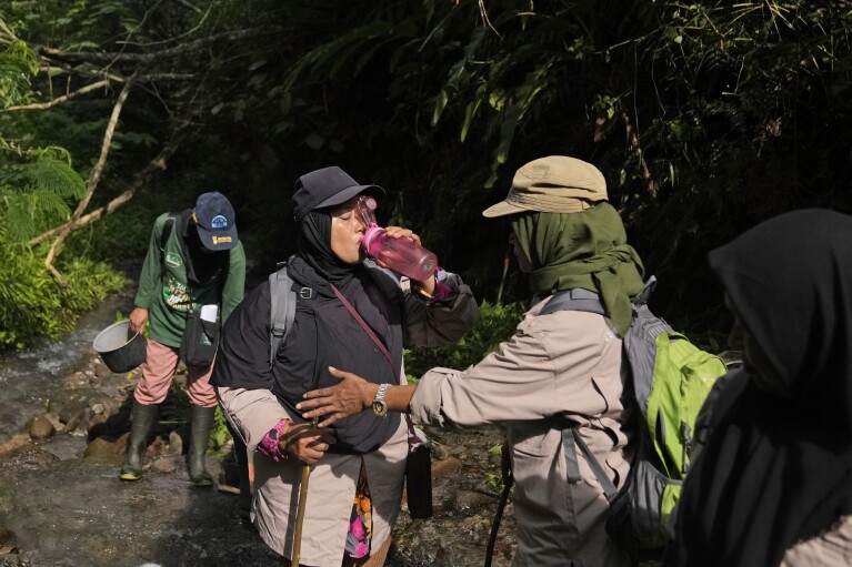 Asmiah, member of female ranger group, drinks from a water bottle during a forest patrol in Damaran Baru, Aceh province, Indonesia, Tuesday, May 7, 2024. The group of forest rangers are defying social norms to lead patrols in the jungle to combat deforestation. (AP Photo/Dita Alangkara)