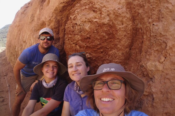 In this undated photo provided to the Associated Press by Stellenbosch University researcher, Michele Francis, right, and other researchers, pose for a selfie, next to an ancient termite mound in Namaqualand, South Africa. Scientists have been stunned to discover that termite mounds that are still inhabited in an arid region of the country are more than 30,000 years old, meaning they are the oldest known active termite hills. (Photo/Michele Francis via AP)