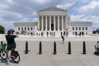 Visitors pose for photographs at the U.S. Supreme Court Tuesday, June 18, 2024, in Washington. Social media users are falsely claiming that a video shows tall fences blocking access to the building this week. ( AP Photo/Jose Luis Magana)