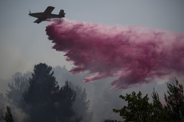 FILE - A plane uses a fire retardant to extinguish a fire burning in an area near the border with Lebanon, in Safed, northern Israel, Wednesday, June 12, 2024. Scores of rockets were fired from Lebanon toward northern Israel on Wednesday morning, hours after Israeli airstrikes killed four officials from the militant Hezbollah group including a senior military commander. (AP Photo/Leo Correa, File)