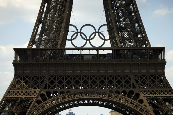 The Olympic rings are seen on the Eiffel Tower from the Beach Volleyball court at the Eiffel Tower stadium, Tuesday, June 25, 2024 in Paris. (AP Photo/Thomas Padilla)