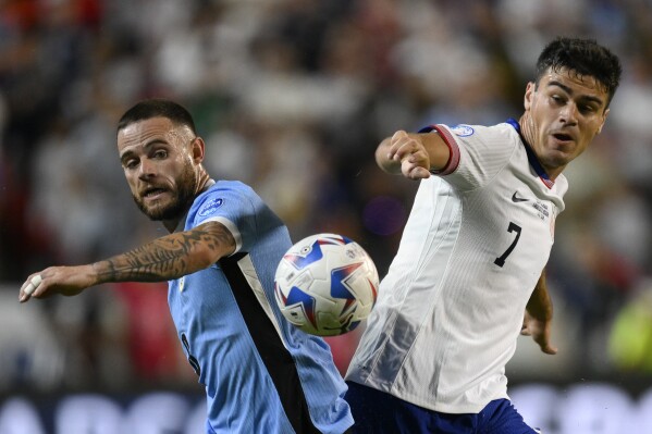 Uruguay's Nahitan Nandez, left, and Gio Reyna of the United States battle for the ball during a Copa America Group C soccer match in Kansas City, Mo., Monday, July 1, 2024. (AP Photo/Reed Hoffman)