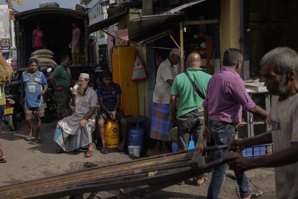 People gather at a street side food seller at a market place in Colombo, Sri Lanka, Monday, Nov. 14, 2022. (AP Photo/Eranga Jayawardena)